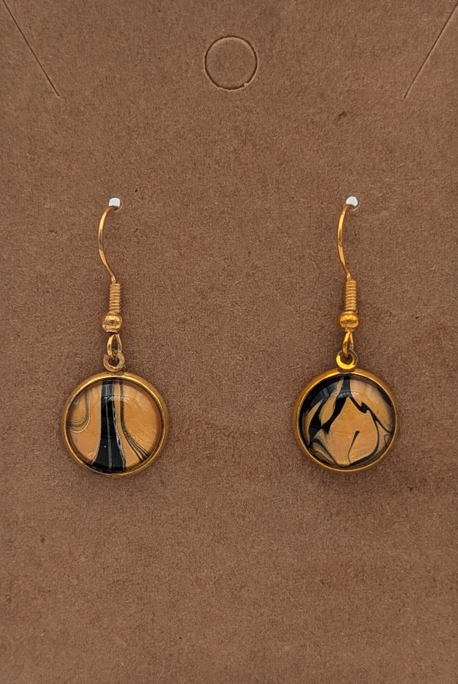 Pair of gold earrings with circular designs on a brown background